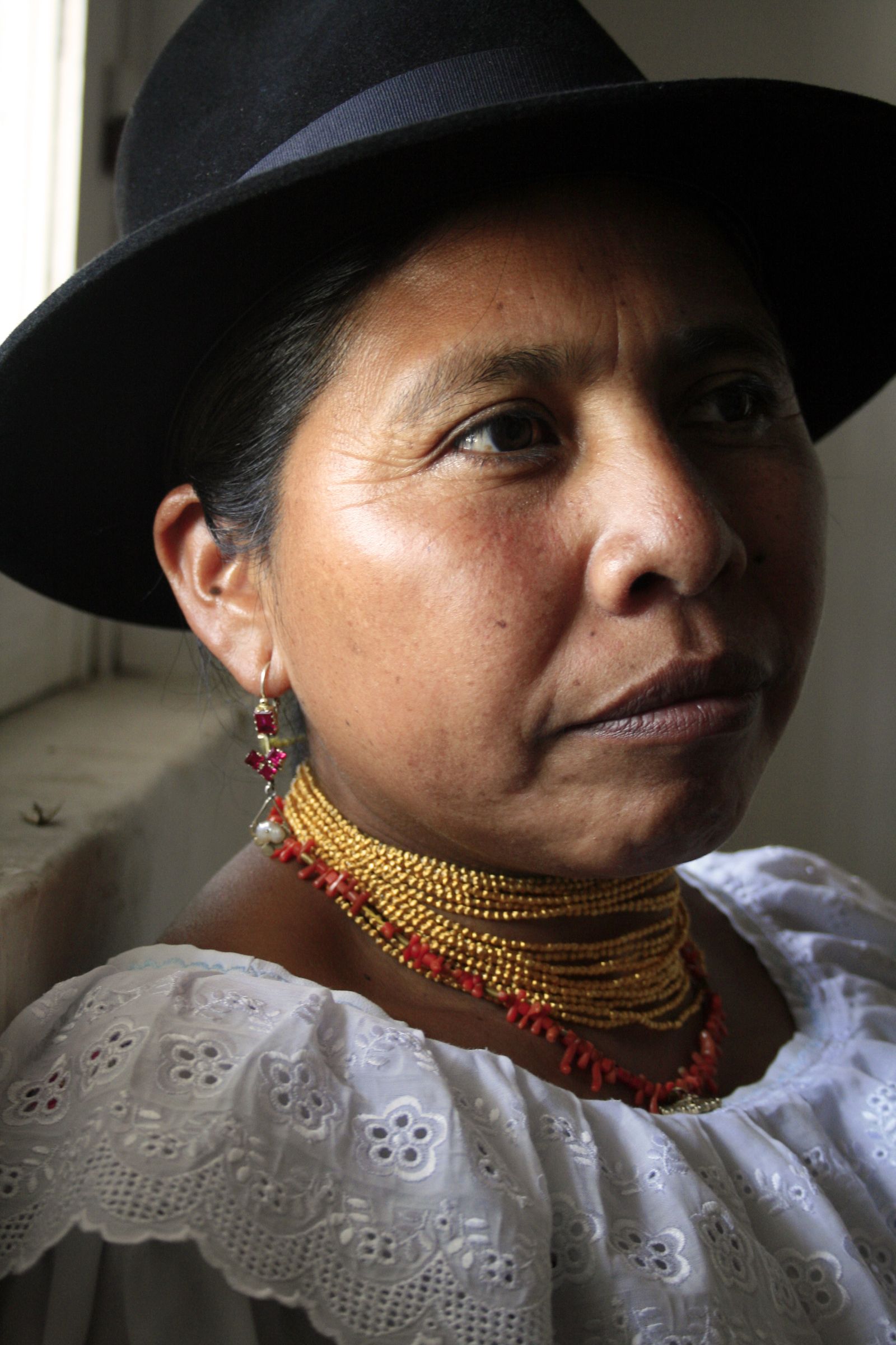 Portrait of a Kichwa woman in a black hat and gold beads