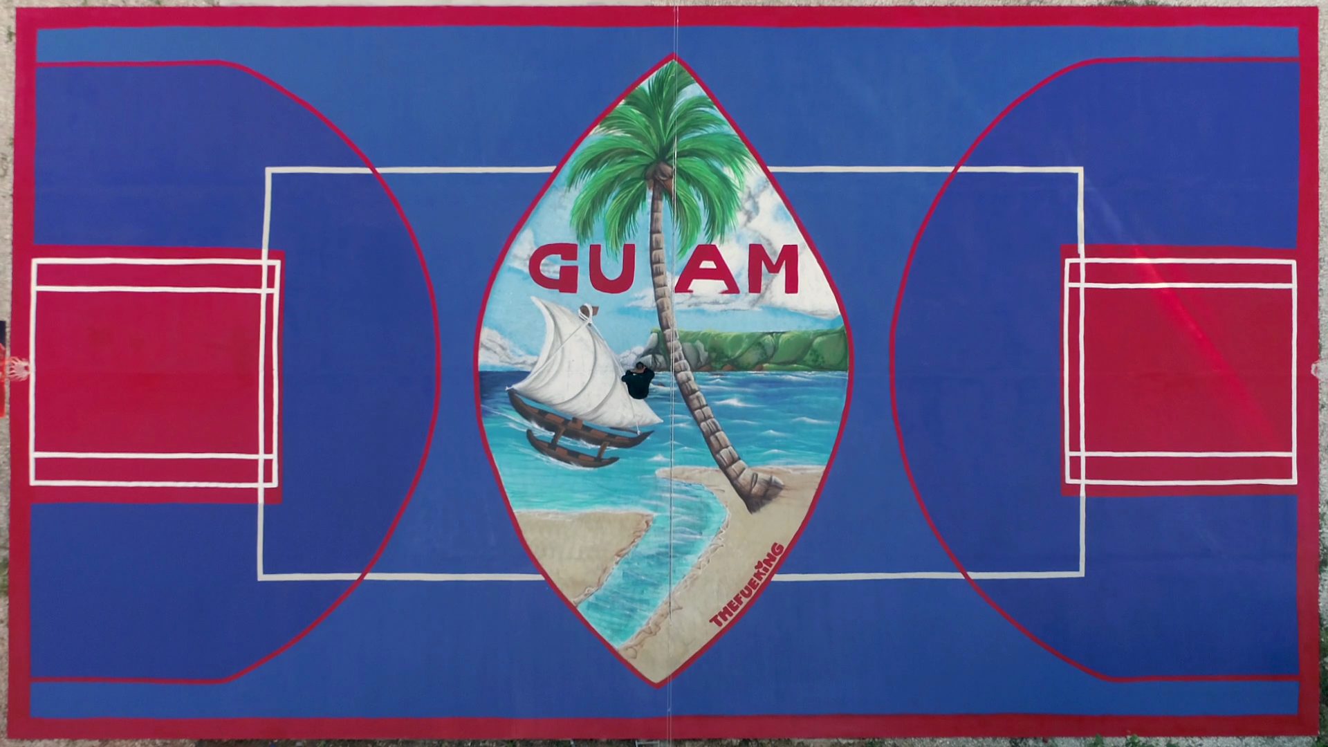 Aerial view of a basketball court painted with a Guam seal mural